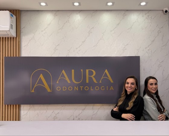 Recepção da Aura Odontologia em Maringá, com o painel da clínica e as doutoras